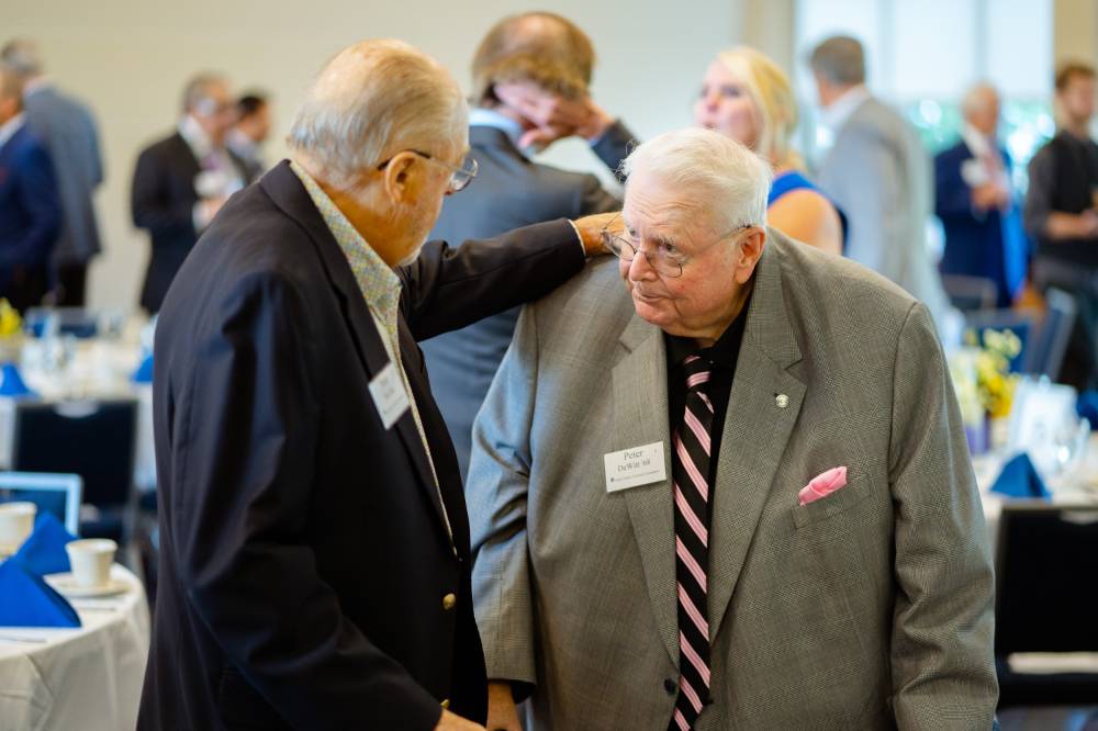 Seymour Padnos putting his hand on a guest's shoulder at the Foundation Annual Meeting